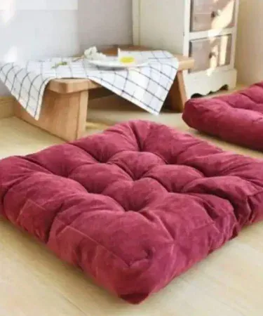 Pair of luxurious square velvet floor cushions in a living room setting.