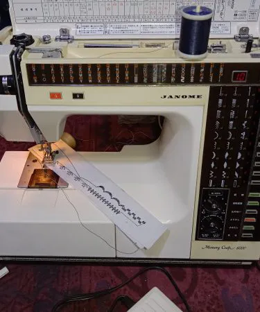 Janome Memory Craft 6000 (110V) computerized sewing machine with included voltage regulator, showing the control panel, free arm, and various accessories on a white background, available via Khareedo Pakistan