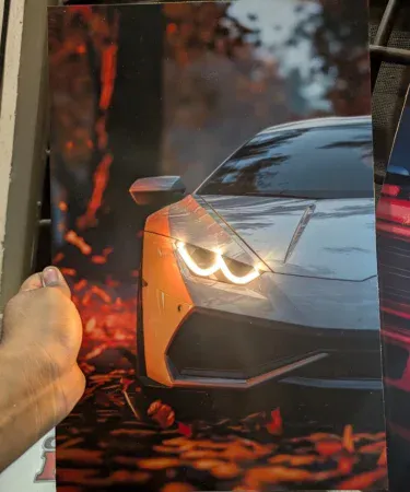 Vibrant Lamborghini Neon LED Light Poster showing the iconic logo glowing in a modern room setup, 12x18 inches, with a car model and gaming setup visible in the background, available for hanging or standing display on Khareedo|Kharedo in Pakistan.