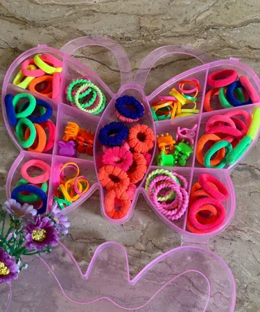 A vibrant pack of multicolored hair accessories for girls, featuring various hair clips, hair bands, and hair ties in different shapes and colors, neatly arranged.