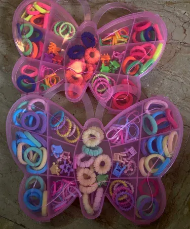 A vibrant pack of multicolored hair accessories for girls, featuring various hair clips, hair bands, and hair ties in different shapes and colors, neatly arranged.