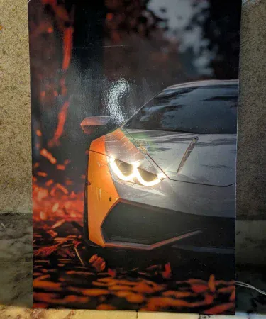 Vibrant Lamborghini Neon LED Light Poster showing the iconic logo glowing in a modern room setup, 12x18 inches, with a car model and gaming setup visible in the background, available for hanging or standing display on Khareedo|Kharedo in Pakistan.