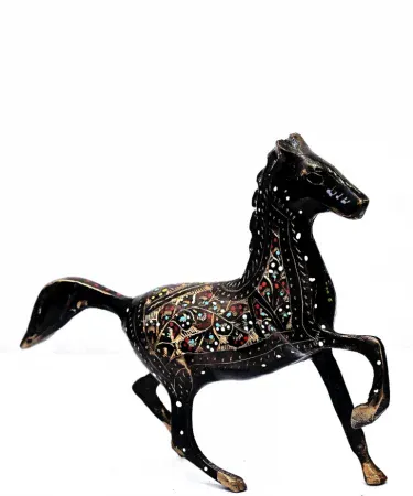 Handcrafted brass horse home decor with golden floral detailing on a wooden shelf, showcasing intricate engraved patterns and a stable base.
