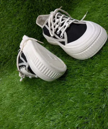 Women’s casual canvas sneakers black and white low‑top shoes with decorative laces on a light background, imagecaption=Stylish black‑and‑white low‑top canvas sneakers for women, featuring decorative laces and a comfortable rubber outsole.