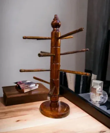 Elegant round jewellery stand with multiple hooks and trays for necklaces, bracelets and rings, displayed on a wooden tabletop.