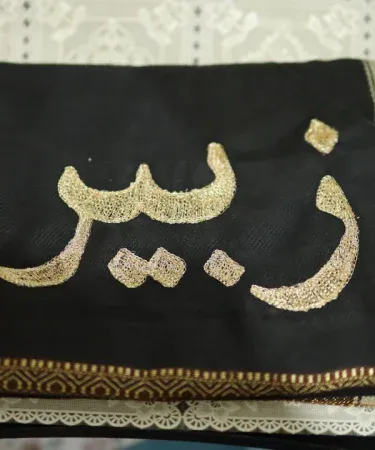 Personalized Afghan Patoo shawl with golden border and custom name embroidery in black, imagecaption=Custom embroidered Afghan shawl – name or logo personalization, perfect gift choice.