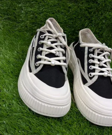Women’s casual canvas sneakers black and white low‑top shoes with decorative laces on a light background, imagecaption=Stylish black‑and‑white low‑top canvas sneakers for women, featuring decorative laces and a comfortable rubber outsole.