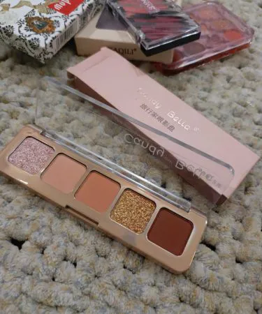 Premium makeup kit with brushes, eyeshadows, lipsticks and foundation displayed on a stylish vanity table.