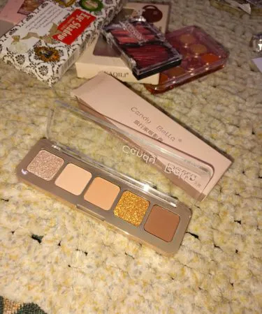 Premium makeup kit with brushes, eyeshadows, lipsticks and foundation displayed on a stylish vanity table.