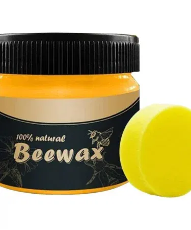 Natural beeswax polish in a white jar with a wooden brush, showing the creamy texture ready for application on wood and leather surfaces.