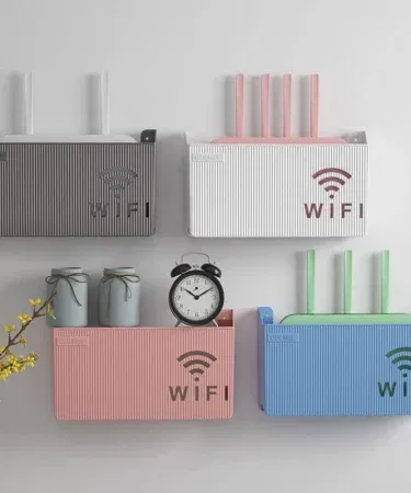 Wall mounted wireless WiFi router shelf made of ABS plastic in random color, mounted on a modern home wall showing ventilation slots and clean cable management, imagecaption=Stylish wall‑mounted router shelf keeping your WiFi device organized and cool.
