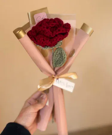 Handmade crochet red rose single stem wrapped bouquet with gold ribbon and “With Love” tag, imagecaption=Elegant handmade crochet red rose ready for gifting – perfect for Valentine’s Day, birthdays, and anniversaries.