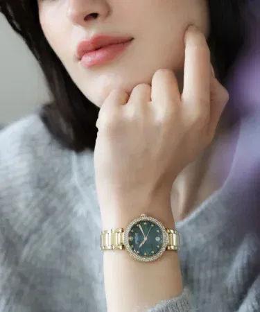 Elegant gold women's watch with green dial, crystal bezel, and date display, sold in Pakistan.